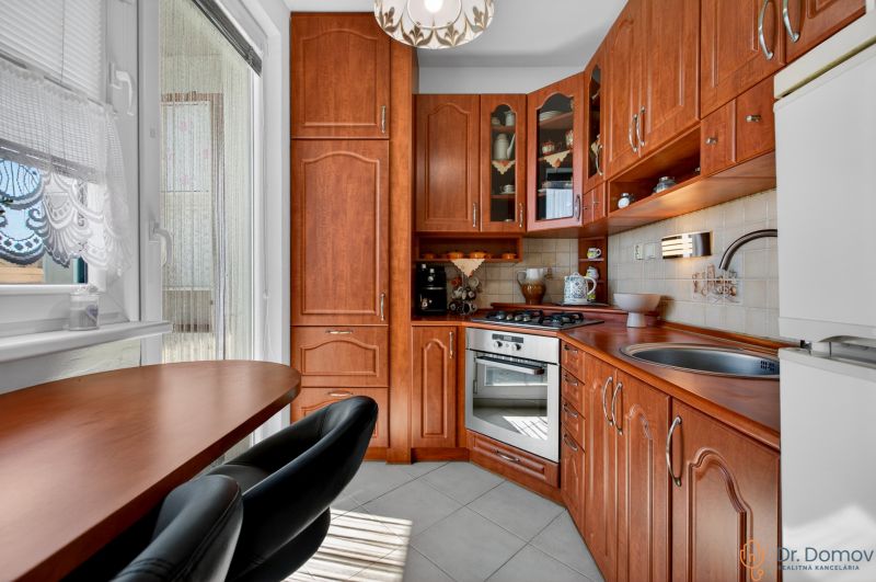 Compact kitchen in a 2-room apartment with wooden decor and kitchen appliances.