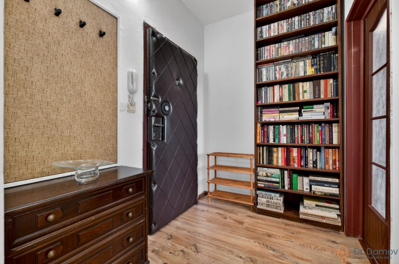Entrance hallway of a 2-room apartment with bookshelves and a floor with a wood decor.