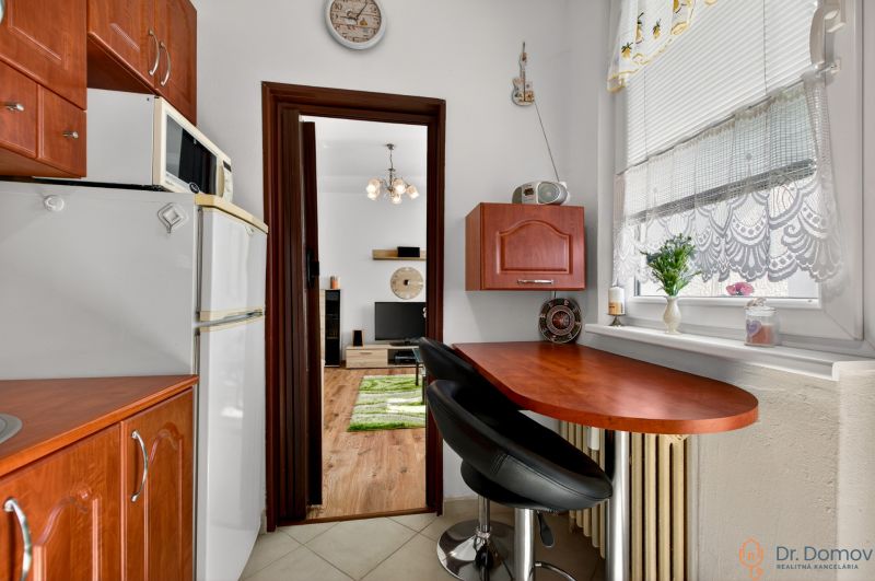 A kitchen in a 2-room apartment with a wooden decor kitchen unit and a bar counter.