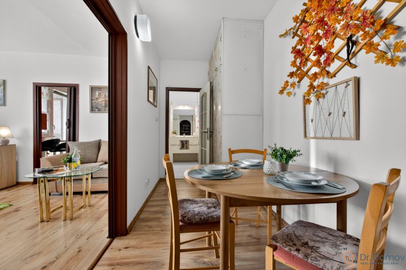 Interior of a 2-room apartment with a dining table, wooden decor flooring, and autumn decorations.