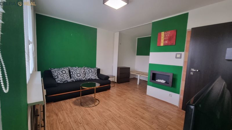 Living room with a sofa, green walls, wood-patterned flooring, and modern lighting.