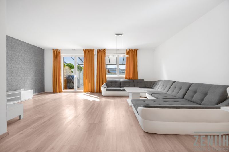 Living room in a family house with a sofa, orange curtains, and a wooden decor floor.