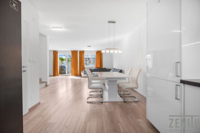 A bright interior of a family house with a kitchen, a wooden decor floor, and orange curtains.