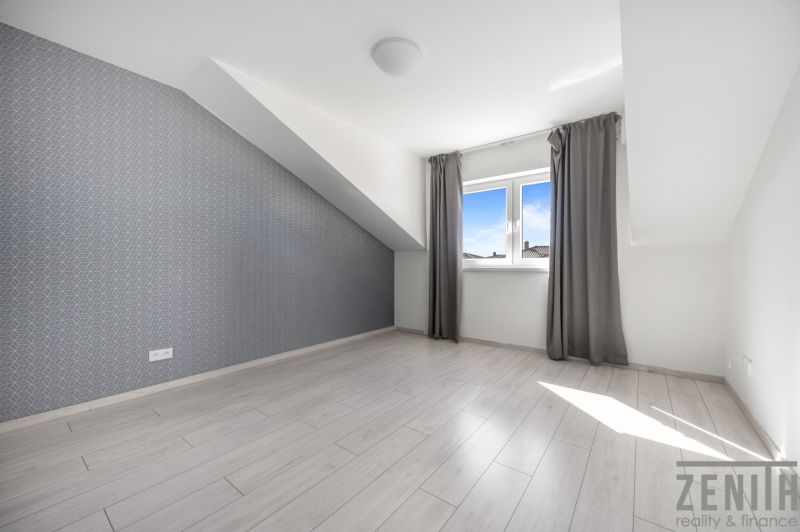 A bright room with a wooden decor floor and a sloped ceiling in a family house.