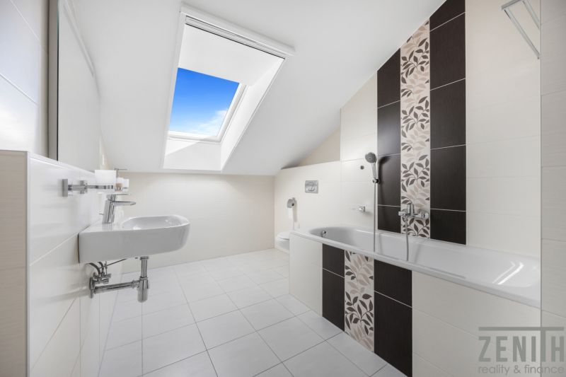 A bathroom in a family house with a large skylight and elegant tiles.