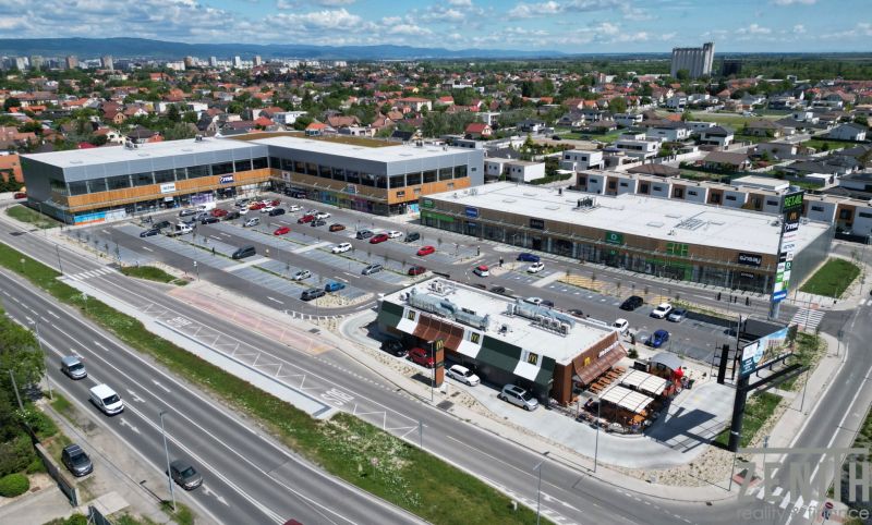 A shopping center with a parking lot in Bratislava - Podunajské Biskupice surrounded by residential buildings.