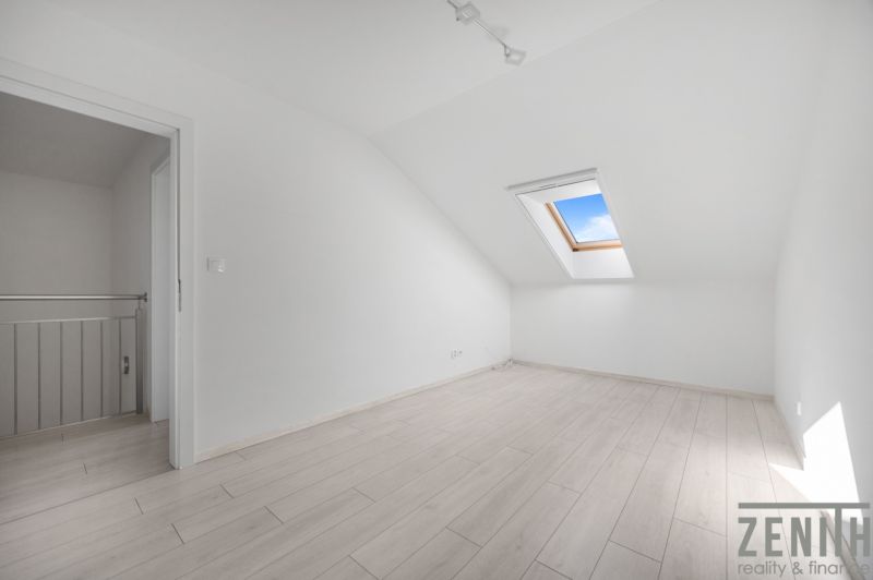 Attic room in a family house with a wooden decor floor and a skylight.