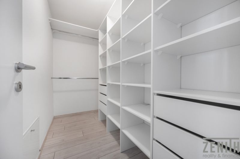 A wardrobe with numerous shelves and drawers in a family house with a wooden decor floor.
