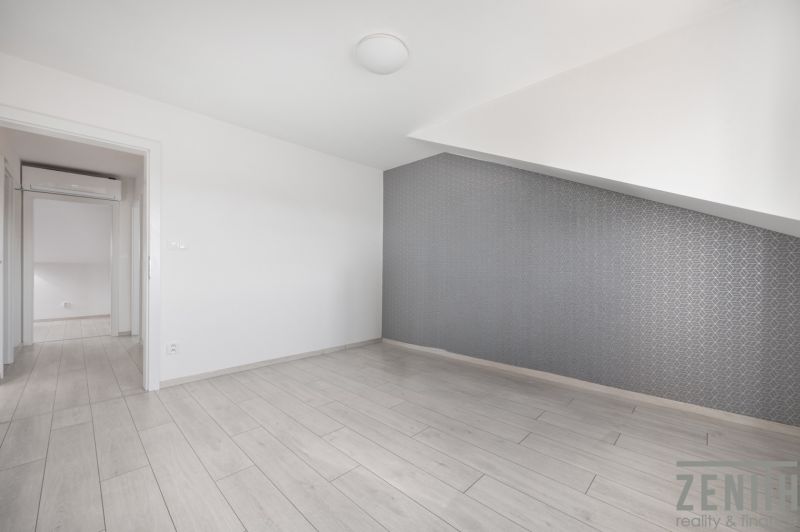 A room in a family house with a wooden decor floor and a patterned wall.