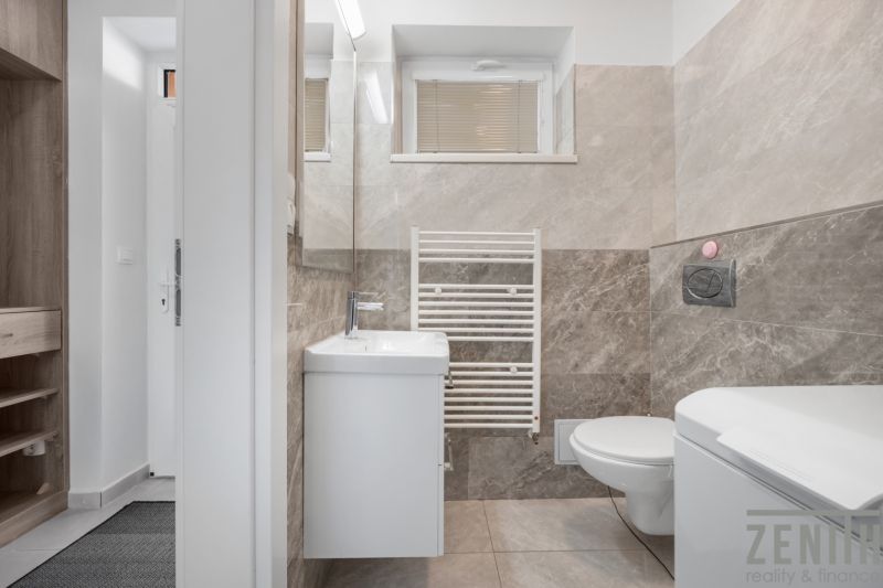 A bathroom with beige tiles and white accessories in a family house.