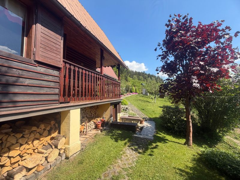 A cottage on Bukovská Road in Čadca with wooden cladding and a garden with a red tree.