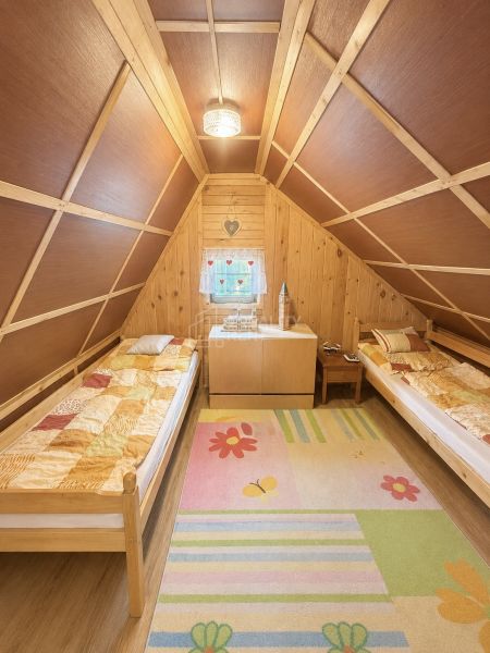 The interior of a cabin with two beds and a floor with wooden decor and a colorful carpet.