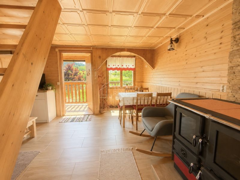 Wooden interior of a cabin with a kitchenette and a sofa, floor with wooden decor.