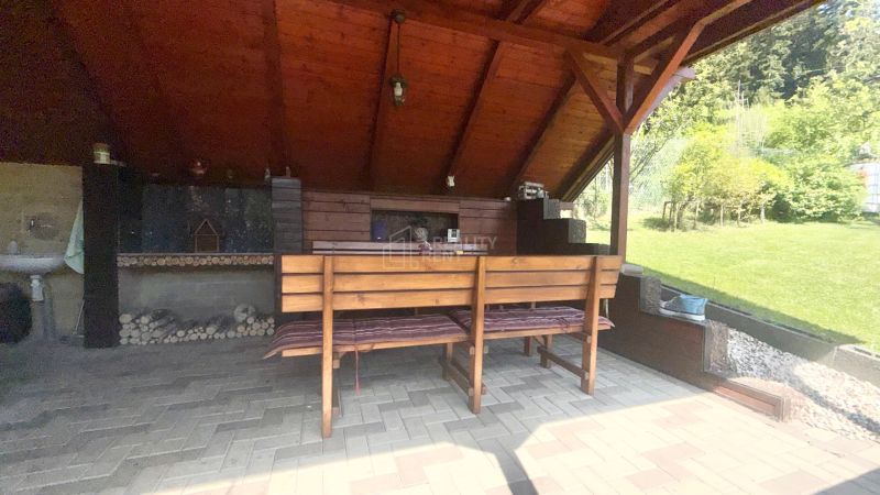 Covered terrace on Bukovská Road in Čadca with a brick floor and wooden seating by the cottage.