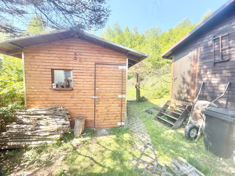 A cottage on Bukovská Road in Čadca with a wooden shed and a pile of wood.