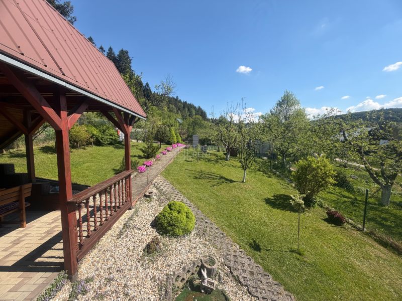 A cottage on Bukovská Road in Čadca with wooden elements, a garden, lawn, and trees.