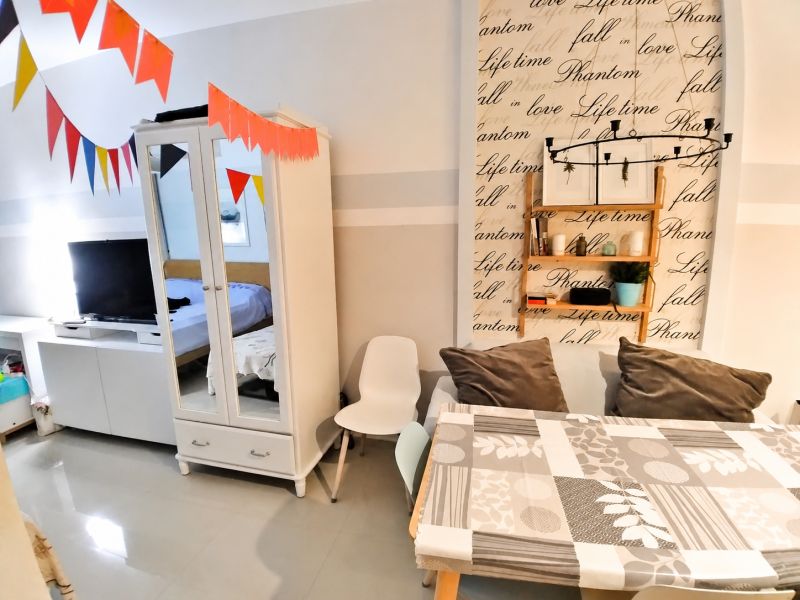 Storage cabinet, table with cushions, and decorative wall in a studio apartment.