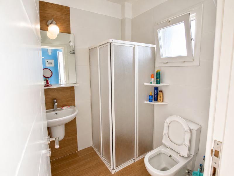 Bathroom in a one-room apartment with a sink, mirror, and shower corner.