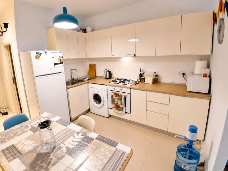 A kitchen in a studio apartment with a gas stove, washing machine, and dining table.