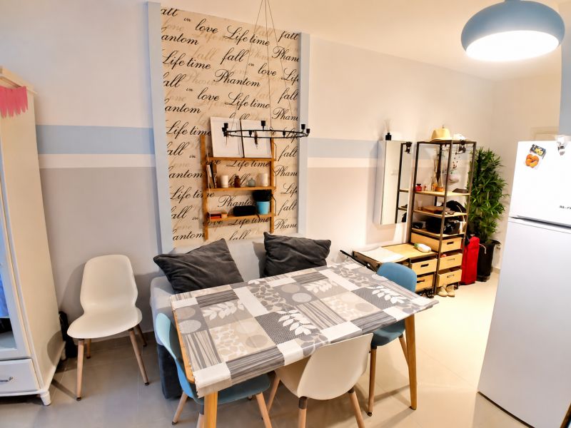 Dining area in a studio apartment with colorful chairs and a decorative wall.