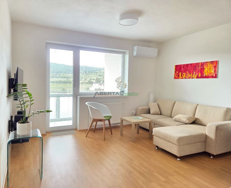 Living room with a sofa, armchair, table, and wooden decor flooring in a 2-room apartment.