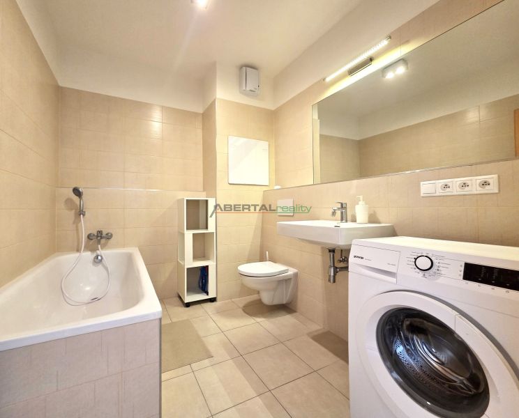 A bathroom with a bathtub, washing machine, sink, and toilet in a 2-room apartment.