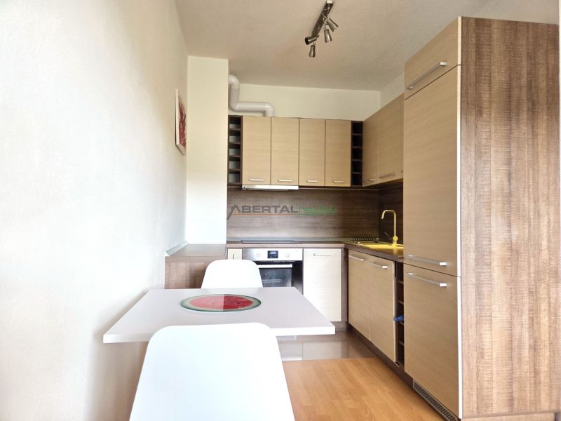 A kitchen in a 2-room apartment with a wood-patterned floor and a white table.