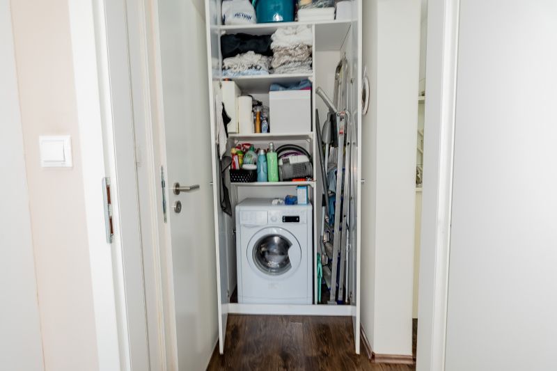 Storage space with a washing machine in a 2-room apartment and a floor with a wooden decor.