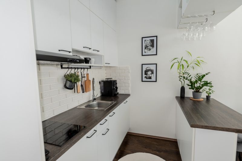 A kitchen in a 2-room apartment with a white brick wall and a wooden decor floor.