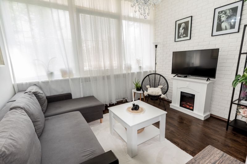 Living room with a comfortable sofa, fireplace, and wooden decor flooring in a two-room apartment.