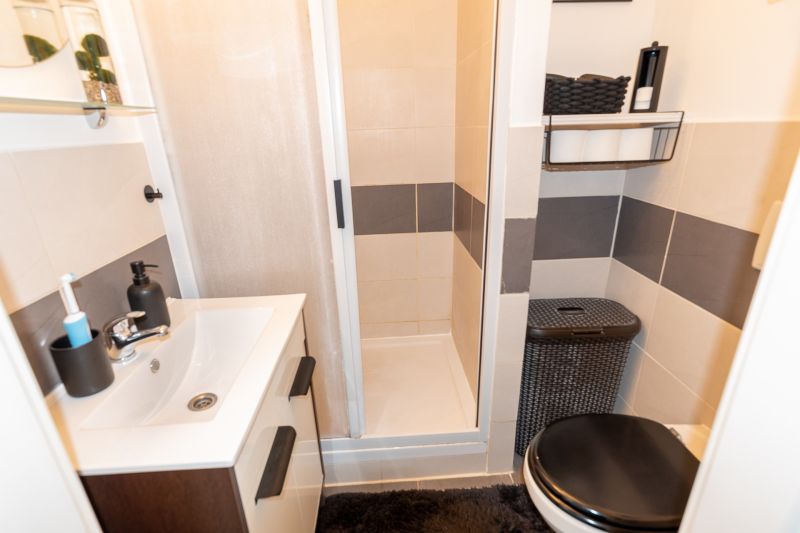 Compact bathroom with a sink, shower, and toilet in a 2-room apartment.