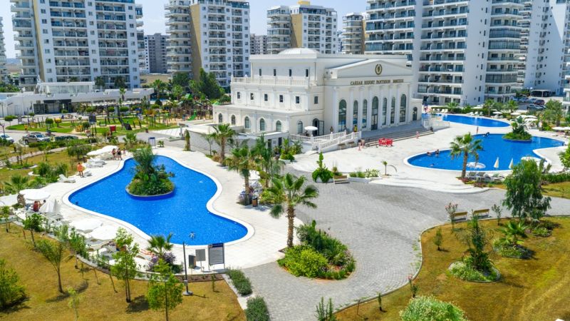 Exterior in Iskele with pools, landscaped gardens, and surrounding apartment complexes.
