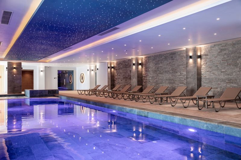 An indoor pool with loungers and a starry effect on the ceiling in a studio apartment.