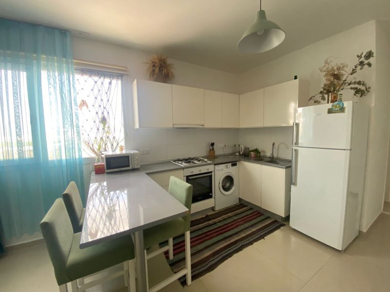 Kitchen in a studio apartment, white furniture, stove, refrigerator, washing machine, dining counter.