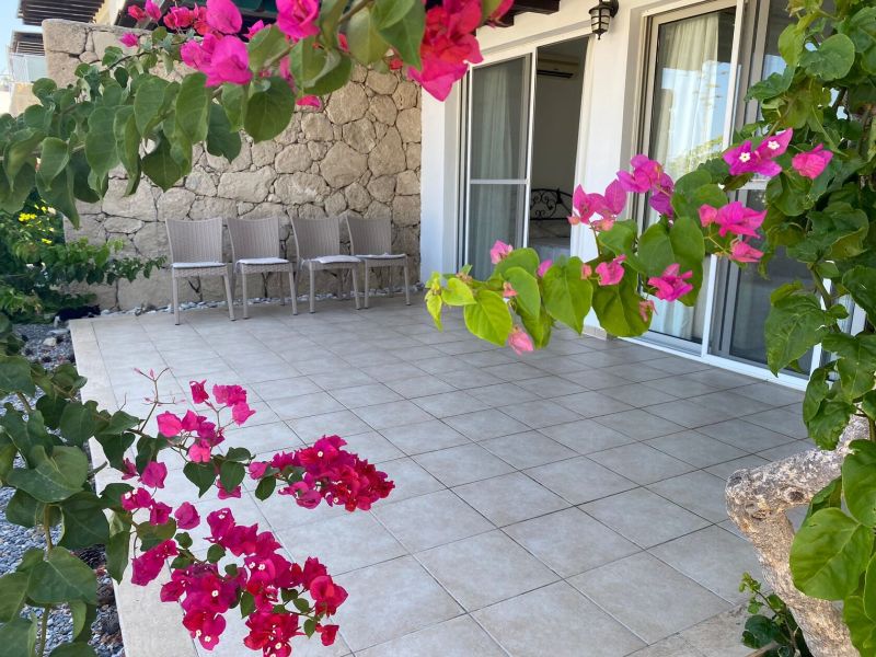 Terrace of a 2-bedroom apartment in Tatlisu with garden furniture and bougainvillea flowers.