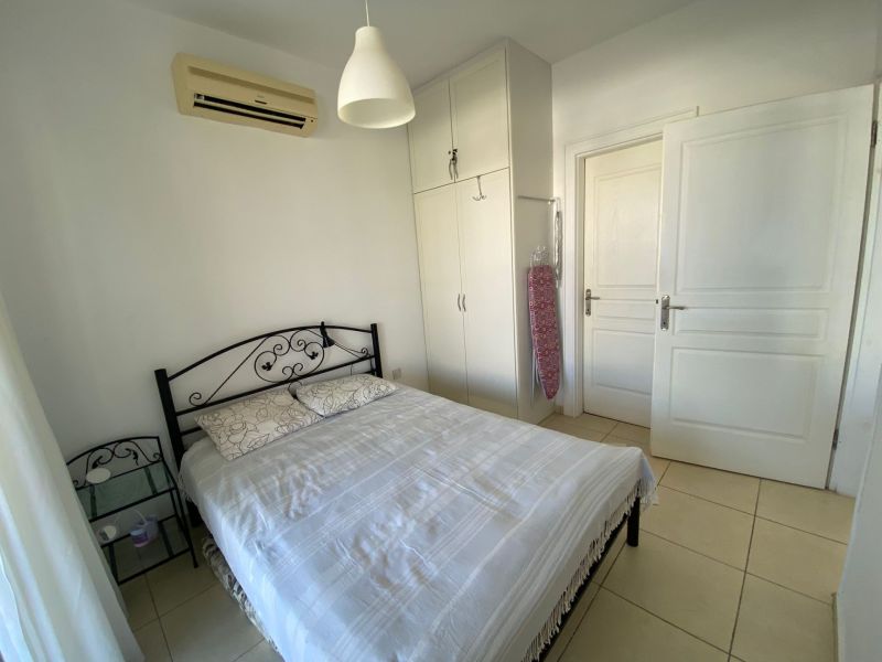 Bedroom in a 2-room apartment with a metal bed, white wardrobe, and air conditioning.
