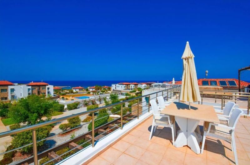 A rooftop terrace with a sea view in Tatlisu, surrounded by green gardens and a swimming pool.