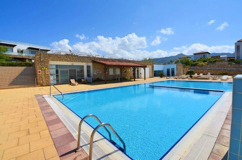 Exterior of a 2-bedroom apartment in Tatlisu with a sunken pool and loungers.