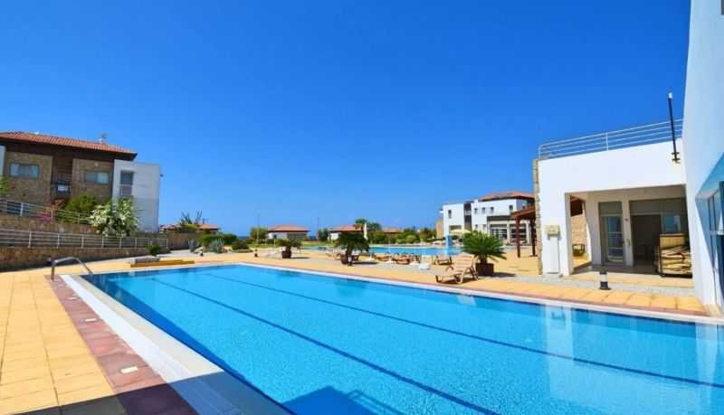 In the outdoor environment of Tatlisu, there are pools and modern buildings of a 2-bedroom apartment.