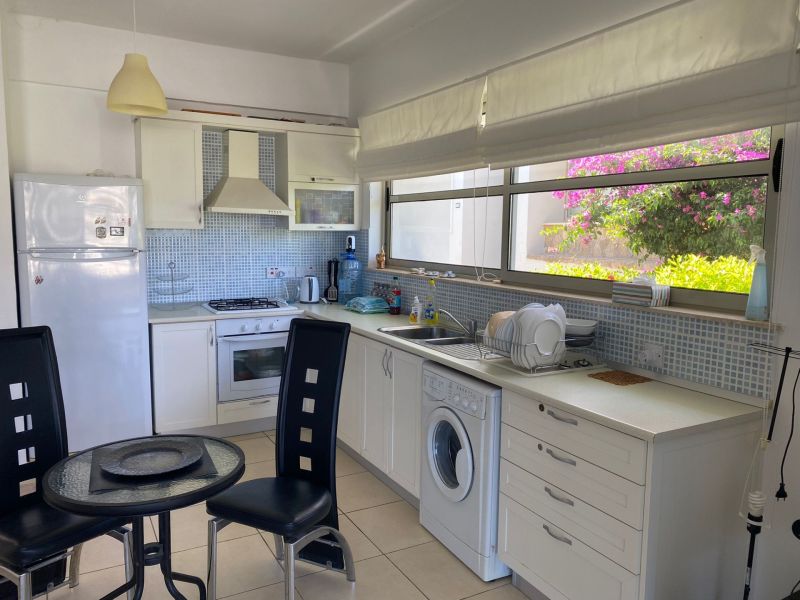 A kitchen in a 2-room apartment with white cabinets and a large window.