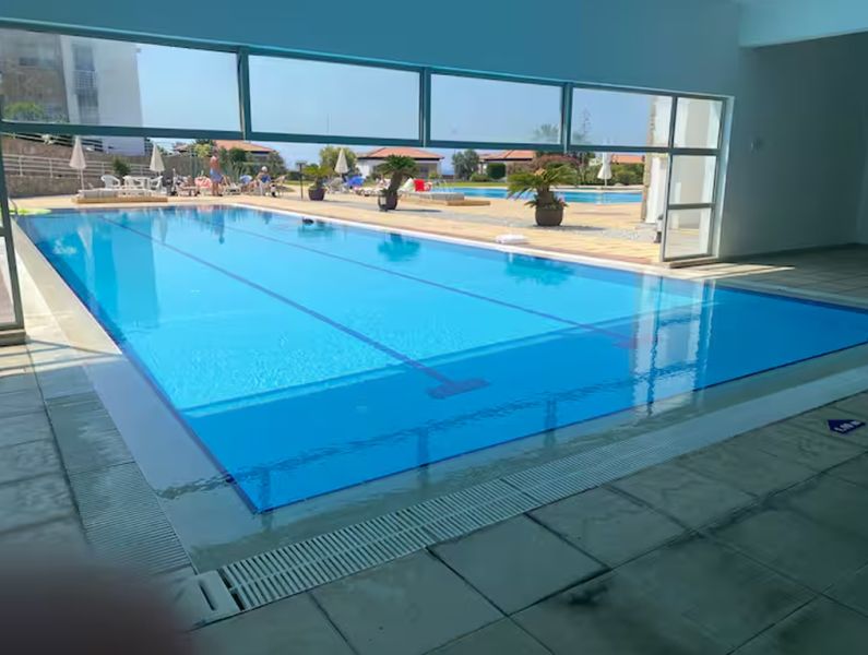 Indoor pool with a view of the exterior area and terrace at a 2-bedroom apartment in Tatlisu.