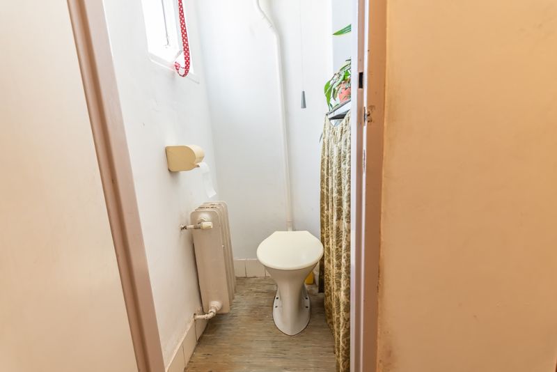 A toilet with a toilet bowl, radiator, and floor with wood decor in a 2-room apartment.