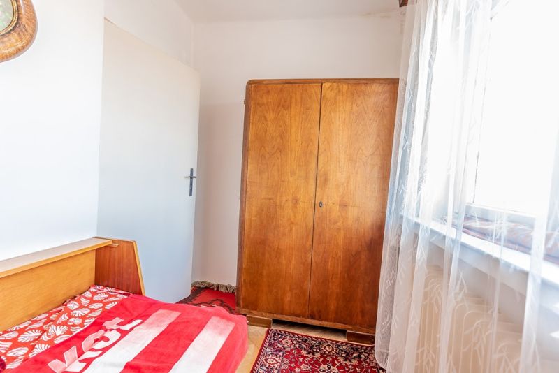 A room with a wooden wardrobe, a bed, and a red carpet in a 2-room apartment.