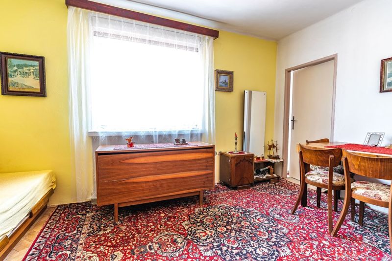 Living room in a two-room apartment with a patterned carpet and wooden furniture.
