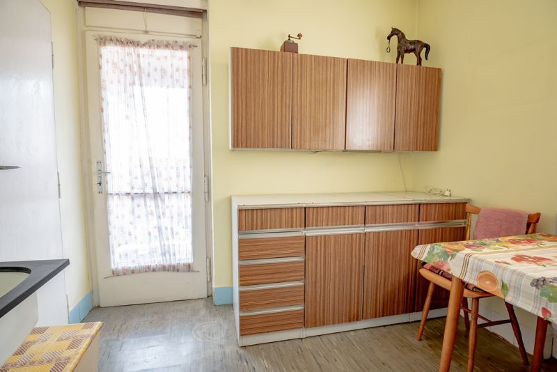 Kitchen of a 2-room apartment with retro cabinets and a dining table.