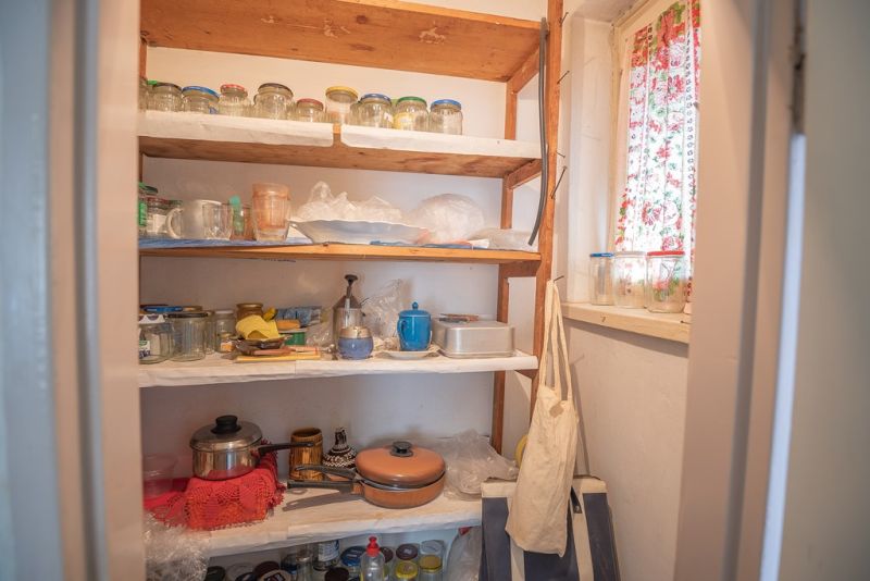 A pantry in a 2-room apartment with wooden shelves and jars for canning.