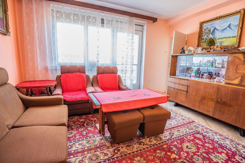 Living room in a 2-room apartment with furniture, a painting, and a wooden decor floor.