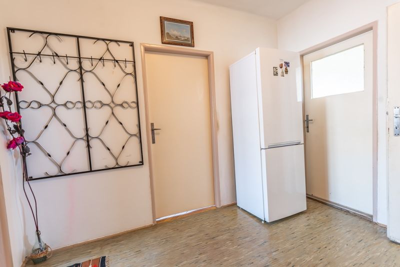 Entrance hallway with a cabinet, coat rack, picture, and floor with wooden decor in a 2-room apartment.