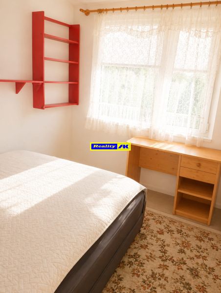 Interior of a 3-room apartment with a bed, a desk, and a red shelf.