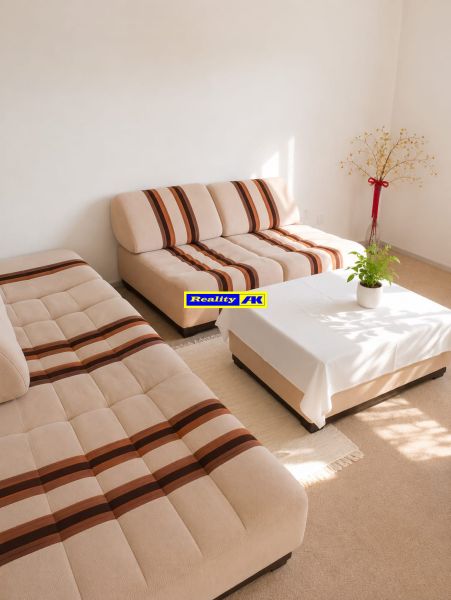 Living room in a 3-room apartment with light sofas and a decorative plant.